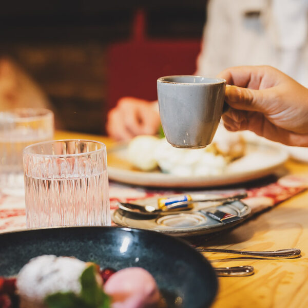 Eiene Dame hebt die Espressotasse zum Schokoladenküchlein mit flüssigem Kern
